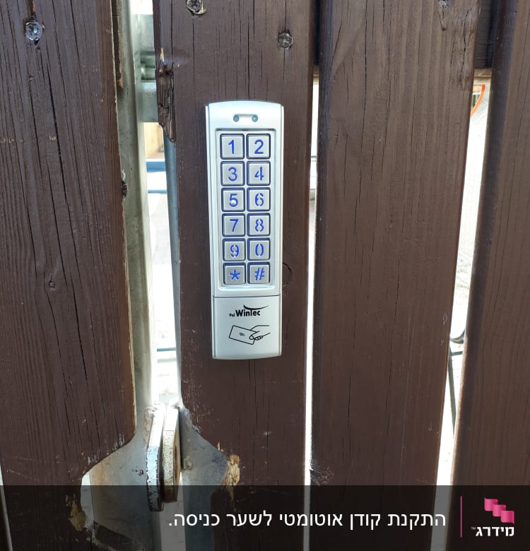 לוח מקשים של אינטרקום מותקן על שער עץ חום